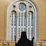 Large Greek Cathedral window detail with silouette of bishop in foreground.