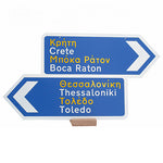 Two signs Grecian signs placed on top of each other with Greek and American cities painted. 